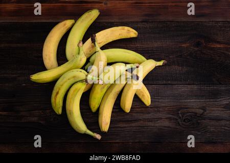 Bananen auf einem Holztisch. Eine reife grüne und gelbe Banane auf dem Küchentisch. Stockfoto