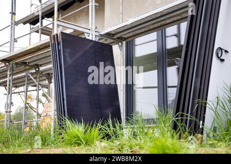 Solarpaneele warten auf Installation neben Gerüsten auf einer Baustelle Stockfoto