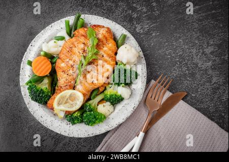 Lachssteak mit Gemüse Blumenkohl, Brokkoli, Karotten und grünen Bohnen. Salat aus Rucola und Gemüse mit Lachs. Draufsicht, flach Stockfoto