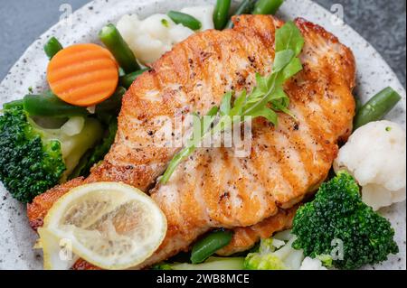 Lachssteak mit Gemüse Blumenkohl, Brokkoli, Karotten und grünen Bohnen. Salat aus Rucola und Gemüse mit Lachs. Nahaufnahme Stockfoto