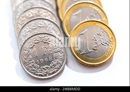 Euro- und Schweizer Franken-Münzen auf weißer Oberfläche. Wert des Schweizer Franken und des Euro und Wechselkursentwicklung. Schweizer Franken vs. CHF. Stockfoto