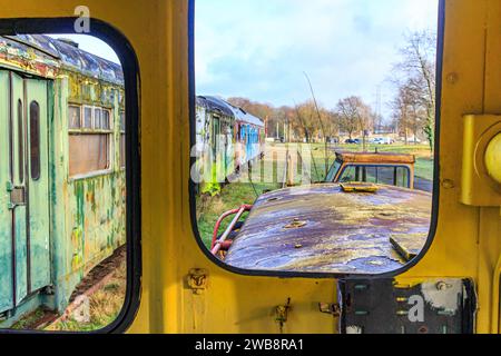 Verkleidungen im sehr alten zerlegten Eisenbahncockpit, Metall korrodiert und rostet im Laufe der Zeit, grüner Personenwagen durch Fenster gesehen in verschwommenem b Stockfoto