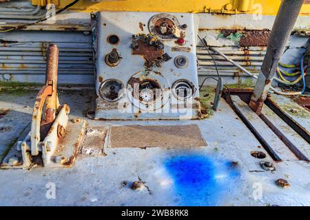 Kleine Schalttafel und Hebel in einem sehr alten zerlegten Eisenbahncockpit, Metall korrodiert und rostet durch die Zeit, Kabel, grau lackiertes Metall Stockfoto