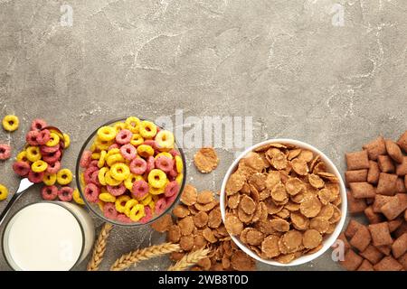 Auswahl an Müsli in Schüsseln, schnelles Frühstück und Milch auf grauem Hintergrund. Draufsicht Stockfoto