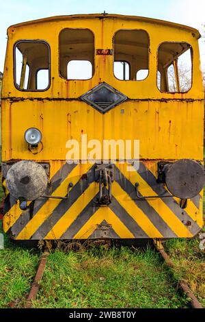 Vorderansicht der abgebauten alten gelb ruinierten Eisenbahnkontrollkabine, Fenster ohne Glas und Kupplungsstopfen, stillgelegte Gleise am alten Bahnhof, rostig Stockfoto