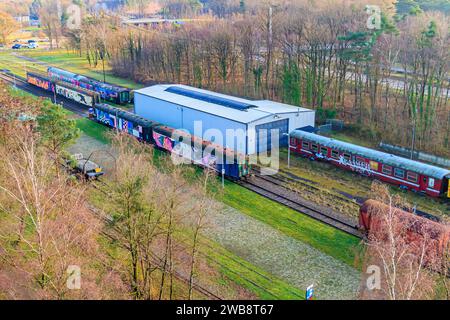 As, Limburg Belgien. Dezember 2023. Aus der Vogelperspektive des alten Bahnhofs, stillgelegte Gleise mit Güter- und Personenkraftwagen, bemalt mit Graffiti, Eisenbahn Stockfoto