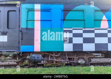 As, Limburg, Belgien. Dezember 2023. Restaurierter Personenwagen, Türen und Fenster in Blau, Rosa und Schwarz lackiert, Bahngleise alter Stati Stockfoto