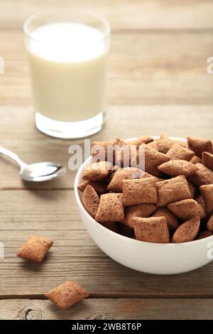 Schokoladenpads, Kornflocken und Milch in der Schüssel auf grauem Hintergrund. Draufsicht Stockfoto