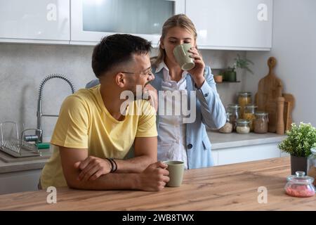 Geschäftskollegen sprechen während der Mittagspause in der Büroküche. Frau kommuniziert mit Arbeitskollegen Kaffeetassen halten Unterhaltung genießen, Arbeit besprechen oder p Stockfoto