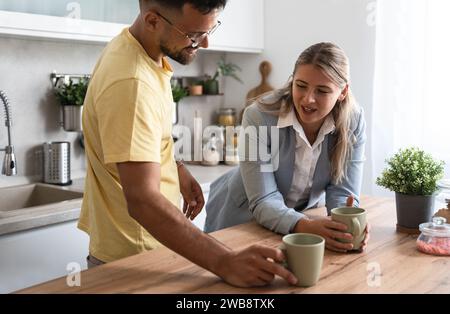 Geschäftskollegen sprechen während der Mittagspause in der Büroküche. Frau kommuniziert mit Arbeitskollegen Kaffeetassen halten Unterhaltung genießen, Arbeit besprechen oder p Stockfoto