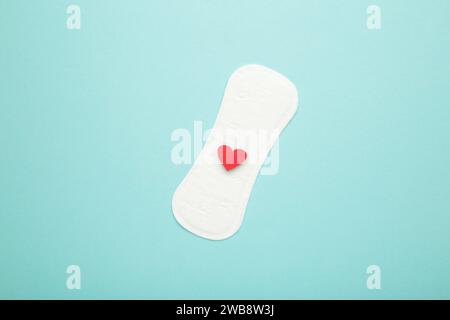 Menstruationspads auf blauem Hintergrund. Menstruationszyklus. Hygiene und Schutz. Ein Herz auf einer Menstruationsplatte. Draufsicht. Stockfoto