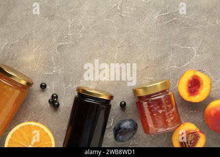 Hausgemachte Obstmarmelade im Glas mit frischem Obst und Beeren auf grauem Hintergrund. Stockfoto