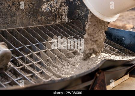 Der Betonmischwagen lieferte nassen Beton und entladete ihn in die Betonpumpe. Laden von Beton aus einem Betonmischer in die Betonpumpe für p Stockfoto