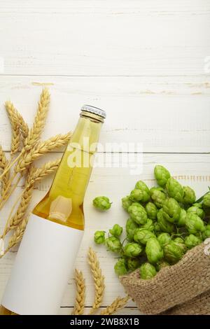 Bierflasche mit Hopfen und Weizen auf weißem Hintergrund, Nahaufnahme. Draufsicht Stockfoto