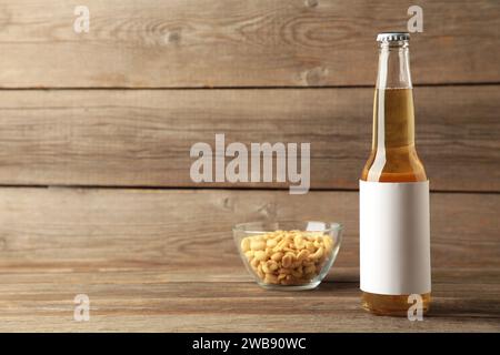 Flasche Bier mit Erdnüssen auf grauem Holzhintergrund. Draufsicht Stockfoto