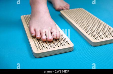 Eine Frau tritt einen Fuß auf ein Sadhu-Yoga-Brett aus Holz mit scharfen Metallnägeln. Ein Werkzeug zum Arbeiten mit Körper und Energie. Nahaufnahme. Stockfoto