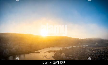 Am frühen Morgen bricht die Sonne über dem Kamm über Loch na Bà Ruaidhe auf dem Culnakirk zwischen Drumnadrochit und Kiltarlity an einem kalten Wintermorgen auf. Stockfoto