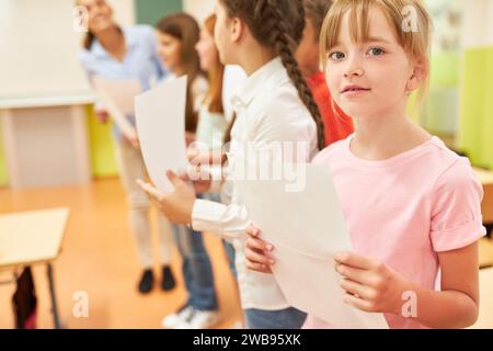 Porträt eines Schulmädchens, der ein Blatt hält, während der Chorpraxis mit Klassenkameraden in der Schule Stockfoto