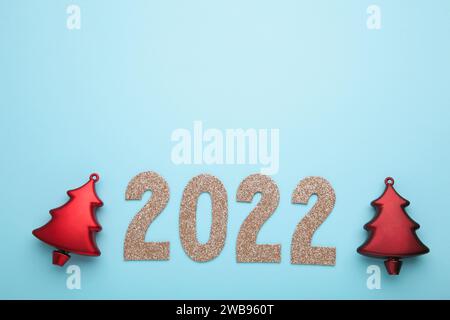 Frohes Neues Jahr 2022. Weihnachtshintergrund mit weihnachtsbaum und Zahlen 2022 auf blauem Hintergrund. Draufsicht Stockfoto