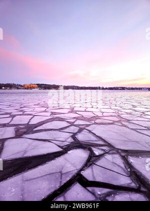 Eisschilde auf dem Meer im Winter bei Sonnenaufgang am frühen skandinavischen Morgen mit violettem und rosa Himmel in der schwedischen Hauptstadt Stockholm mit leichten Wolken am Himmel Stockfoto