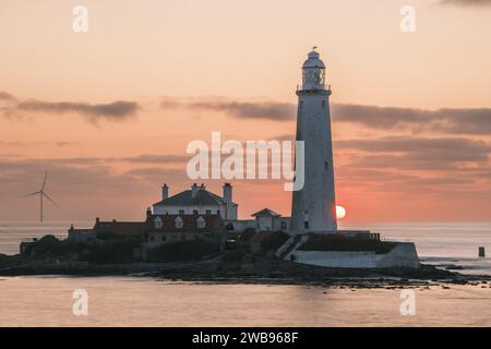 Die Sonne geht an einem wunderschönen Sommermorgen hinter dem St. Mary's Lighthouse in Whally Bay auf. Stockfoto