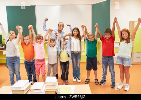 Begeisterte Lehrerin, die mit verschiedenen Schülern anfeuert, während sie im Klassenzimmer steht Stockfoto