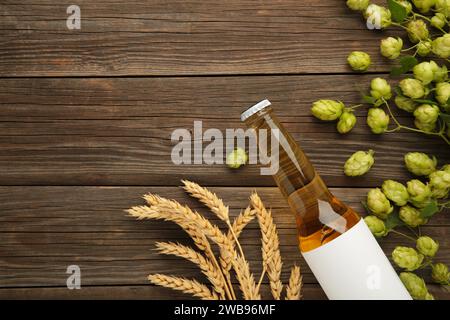 Bierflasche mit Hopfen und Weizen auf grauem Hintergrund, Nahaufnahme. Draufsicht Stockfoto