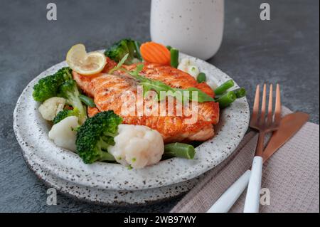 Lachssteak mit Gemüse Blumenkohl, Brokkoli, Karotten und grünen Bohnen. Salat aus Rucola und Gemüse mit Lachs. Stockfoto