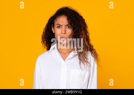 Schwarze junge Dame, die vor Verwirrung runzelte und in die Kamera und das Studio schaut Stockfoto