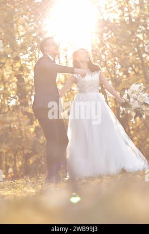 Wunderschönes Hochzeitspaar, das im Freien auf natürlichem Hintergrund an sonnigen Tagen steht Stockfoto