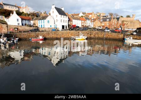 Hübscher Fischerdorfhafen und umliegende Häuser von Crail in Fife Schottland mit Booten und Reflexionen im Wasser Stockfoto