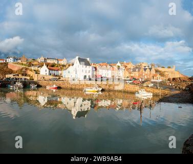 Hübscher Fischerdorfhafen und umliegende Häuser von Crail in Fife Schottland mit Booten und Reflexionen im Wasser Stockfoto