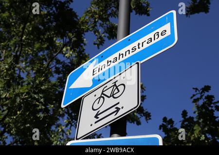 Einweg-Straßenschild in Deutschland, mit zusätzlichem Informationsschild, dass Radfahrer ausgeschlossen sind und beide Wege gehen können. Stockfoto