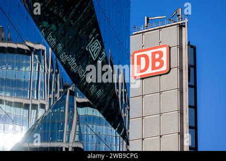 Symbolbild Deutsche Bahn Deutschland, Berlin, am 08.01.2024: das DB Logo in Rot auf einem Turm und im Vordergrund die Reflektion der DB Hauptbahnhof Fassade auf dem Glashaus 3XN Cube. *** Symbolisches Bild der Deutschen Bahn Deutschland, Berlin, am 08 01 2024 das DB-Logo in Rot auf einem Turm und im Vordergrund die Reflexion der DB-Hauptbahnhoffassade auf dem Glashaus 3XN Cube Stockfoto