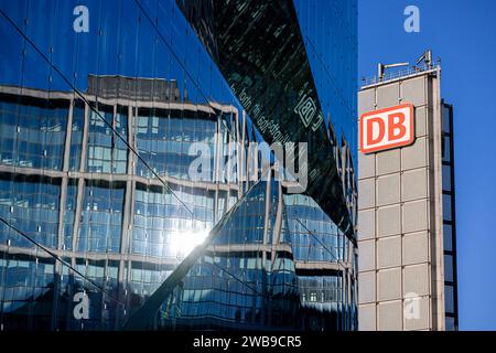 Symbolbild Deutsche Bahn Deutschland, Berlin, am 08.01.2024: das DB Logo in Rot auf einem Turm und im Vordergrund die Reflektion der DB Hauptbahnhof Fassade auf dem Glashaus 3XN Cube. *** Symbolisches Bild der Deutschen Bahn Deutschland, Berlin, am 08 01 2024 das DB-Logo in Rot auf einem Turm und im Vordergrund die Reflexion der DB-Hauptbahnhoffassade auf dem Glashaus 3XN Cube Stockfoto