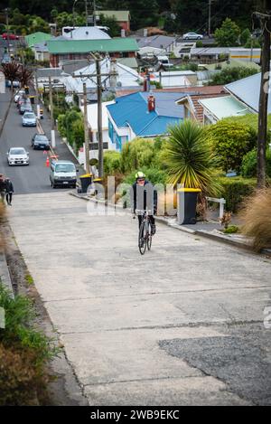 Ein männlicher Straßenradfahrer kämpft um die Baldwin Street, Dunedin, die steilste Straße der Welt. Stockfoto