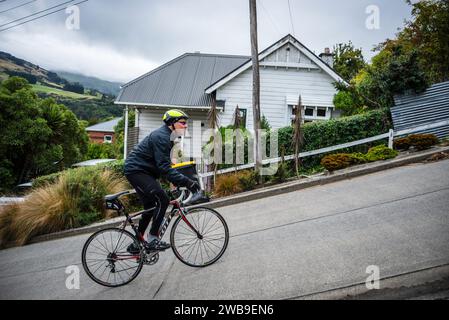 Ein männlicher Straßenradfahrer kämpft um die Baldwin Street, Dunedin, die steilste Straße der Welt. Stockfoto