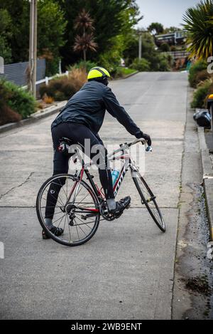 Ein männlicher Straßenradfahrer kämpft um die Baldwin Street, Dunedin, die steilste Straße der Welt. Stockfoto