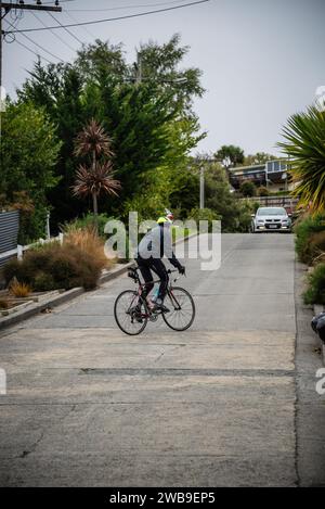 Ein männlicher Straßenradfahrer kämpft um die Baldwin Street, Dunedin, die steilste Straße der Welt. Stockfoto