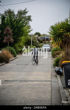 Ein männlicher Straßenradfahrer kämpft um die Baldwin Street, Dunedin, die steilste Straße der Welt. Stockfoto