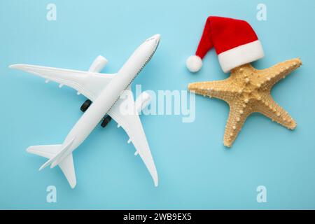 Weihnachtsmann Hut auf Seesternen und weißes Flugzeug auf blauem Hintergrund. Draufsicht. Stockfoto