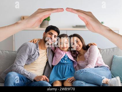 Glückliche interrassische Familie posiert zu Hause unter dem Dach der Hände Stockfoto