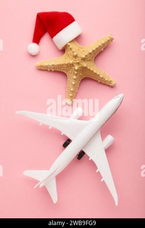 Weihnachtsmann Hut auf Seesternen und weißes Flugzeug auf rosa Hintergrund. Draufsicht. Stockfoto