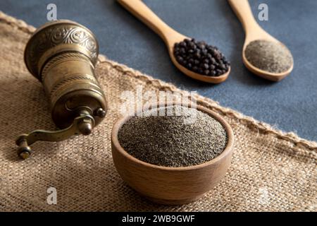 Schwarze Pfeffer, gemahlener schwarzer Pfeffer und Metallmühle auf schwarzem Hintergrund Stockfoto