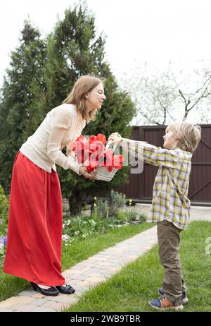 Muttertag, Geburtstag. Die Atmosphäre der Familienliebe, die Zärtlichkeit der Beziehung zwischen Mutter und Sohn. Glückliche Mutterschaft. Der süße 6-jährige Sohn gibt seinen Stockfoto