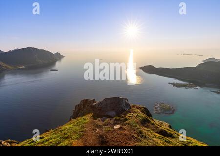 Vom Aussichtspunkt Offersoykammen aus ziehen sich die Sonnenstrahlen über das Wasser und strahlen einen brillanten Glanz über die Landschaft der Lofoten-Inseln aus Stockfoto