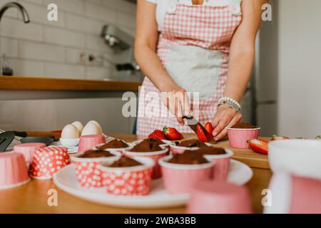Eine junge Frau, die einen frisch gebackenen Cupcake hält. Stockfoto
