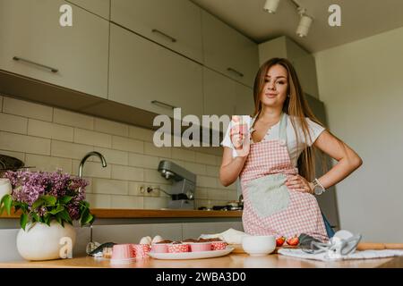 Die Herstellung von roten Samt-Cupcakes. Frau, die Frischkäse auf Cupcake putzt. Stockfoto