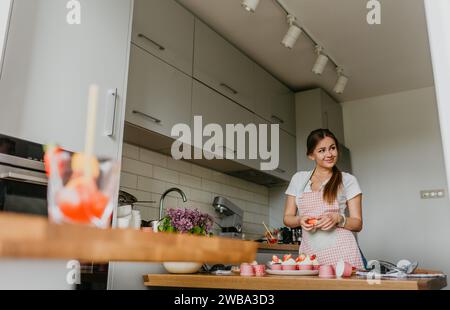 Die Herstellung von roten Samt-Cupcakes. Frau, die Frischkäse auf Cupcake putzt. Stockfoto