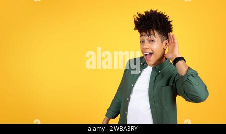 Neugieriger junger Schwarzer, der die Hand neben dem Ohr hält und lauscht Stockfoto